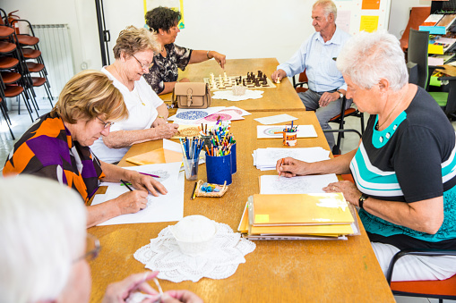 Un grupo de adultos sentados juntos en una mesa y realizando una actividad Art .